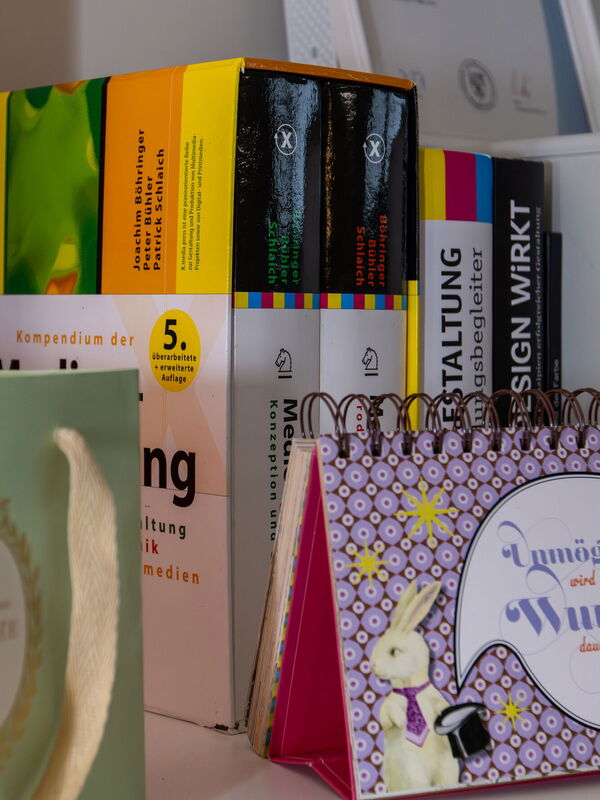 Bücherregal mit Büchern, einem Kalender und einer Geschenktüte